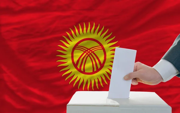 Muž hlasování o volbách v Kyrgyzstán před vlajky — Stock fotografie