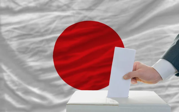 Мужчина голосует на выборах в Японии перед флагом — стоковое фото