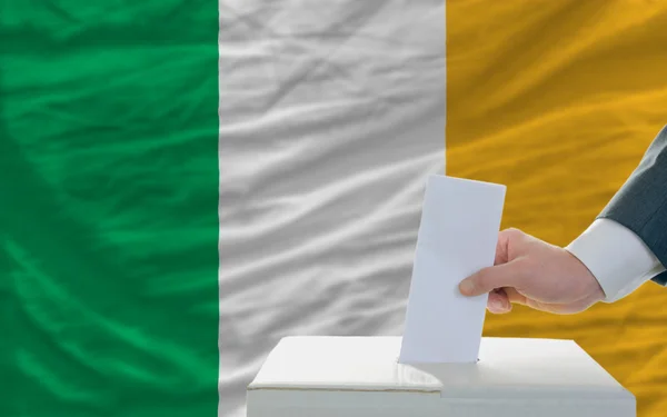 Hombre votando en las elecciones en Irlanda frente a la bandera —  Fotos de Stock