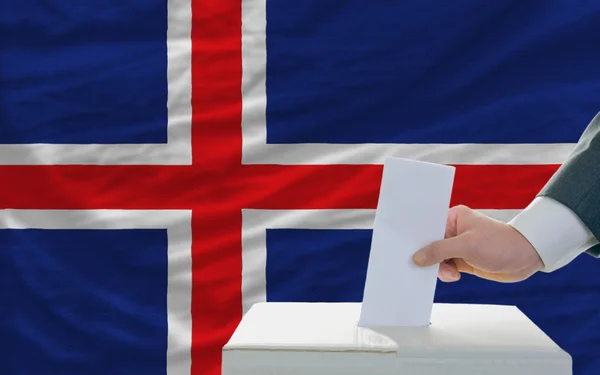 Мужчина голосует на выборах в Исландии перед флагом — стоковое фото