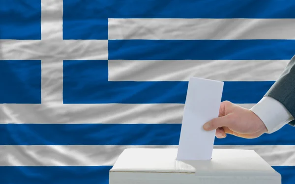 Muž hlasování o volbách v Řecku před vlajky — Stock fotografie
