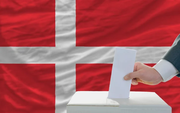 Człowiek głosowania w wyborach w Danii przed flagą — Zdjęcie stockowe