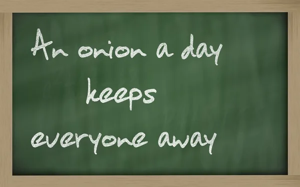 " 一天一个洋葱让每个人都远离"写在黑板上 — 图库照片
