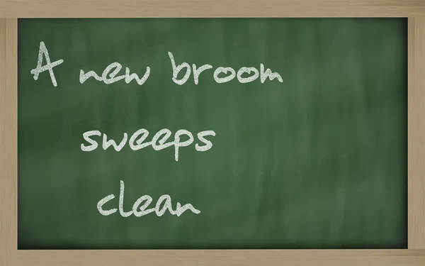 " A new broom sweeps clean " written on a blackboard — Stock Photo, Image