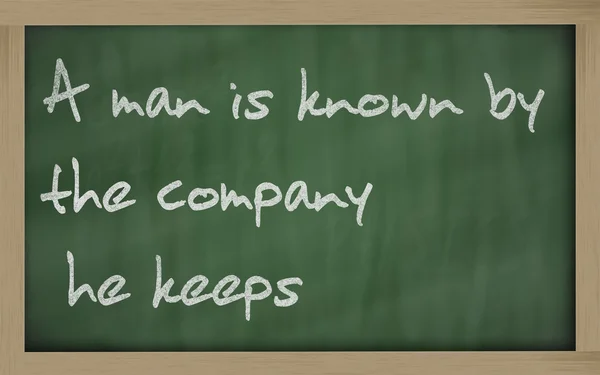 " Een man is bekend door het bedrijf dat hij houdt "geschreven op een blackboa — Stockfoto