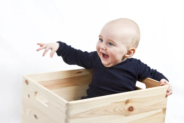 Jeune enfant dans une boîte en bois pointant vers la gauche — Photo