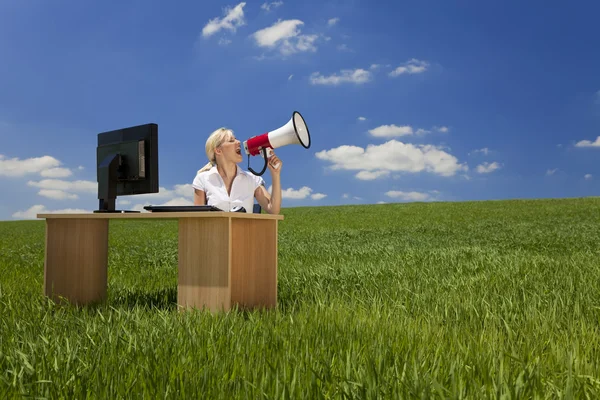 stock image Woman At Desk With Computer Using Megaphone In Green Field