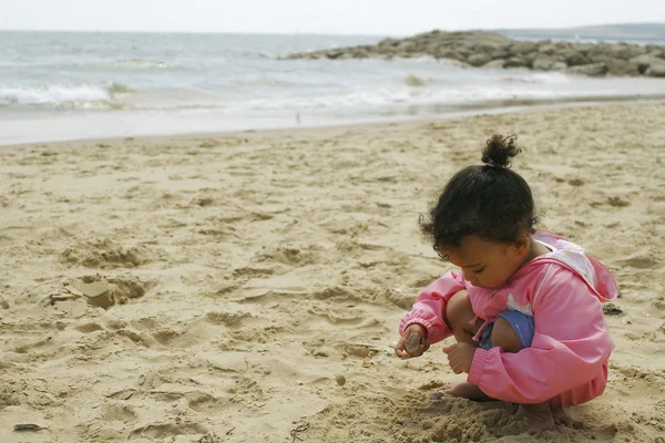 A young mixed race girl plays on a sandy beach — Stock Photo, Image