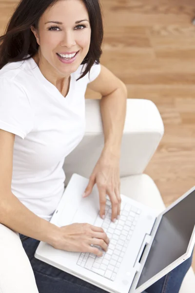 젊은 갈색 머리 여자 소파에 집에서 노트북 컴퓨터를 사용 하 여 — 스톡 사진