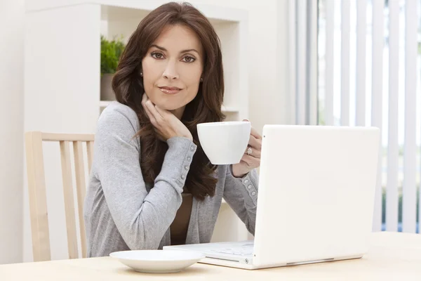 Laptop számítógéppel otthon nő iszik teát vagy kávét — Stock Fotó