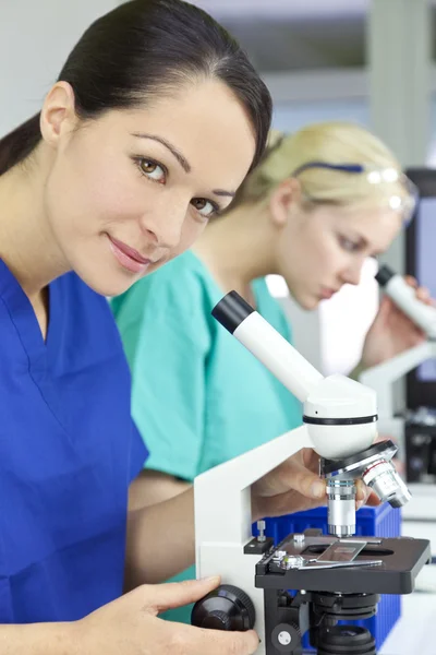 Женщина-ученый или женщина-исследователь с помощью микроскопа в лаборатории — стоковое фото