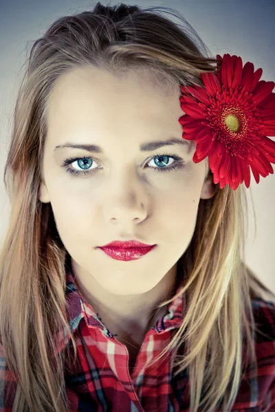 Portrait of young beautiful woman with red flower in her hair — Stock Photo, Image