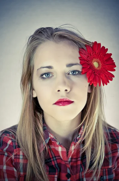 Retrato de jovem mulher bonita com flor vermelha em seu cabelo — Fotografia de Stock