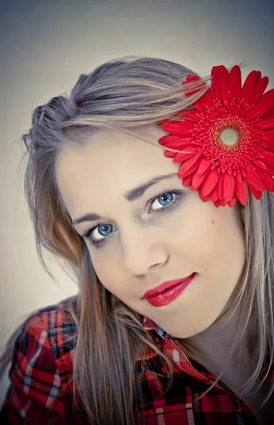 Portrait of young beautiful woman with red flower in her hair — Stock Photo, Image