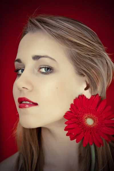 Porträt einer jungen schönen Frau mit roter Blume im Haar — Stockfoto