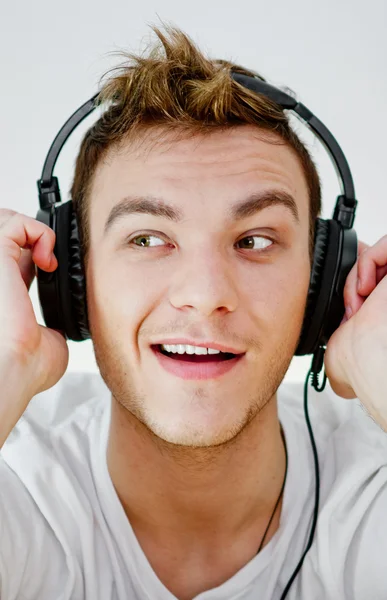 Young man wearing headphones and holding arms on them. — Stock Photo, Image