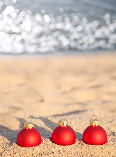 Three red Christmas balls on sea coast — Stock Photo, Image