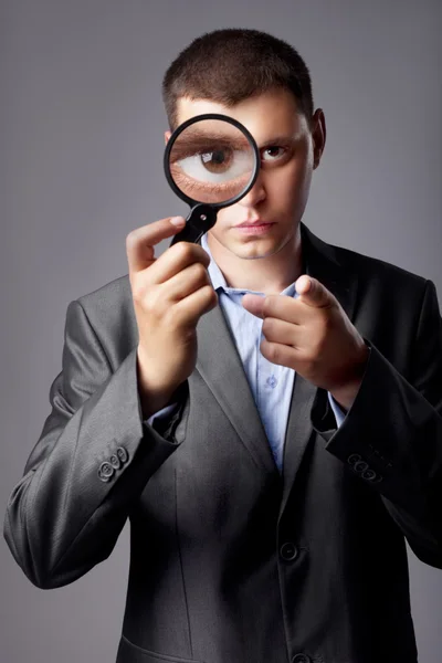 Zakenman in een pak op zoek door een vergrootglas — Stockfoto
