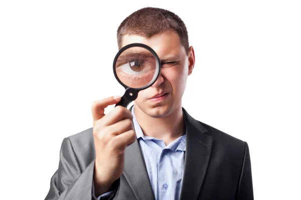 Businessman in a suit looking through a magnifying glass isolate — Stock fotografie