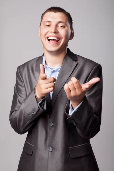 Happy young businessman shows forefingers — Stock Photo, Image