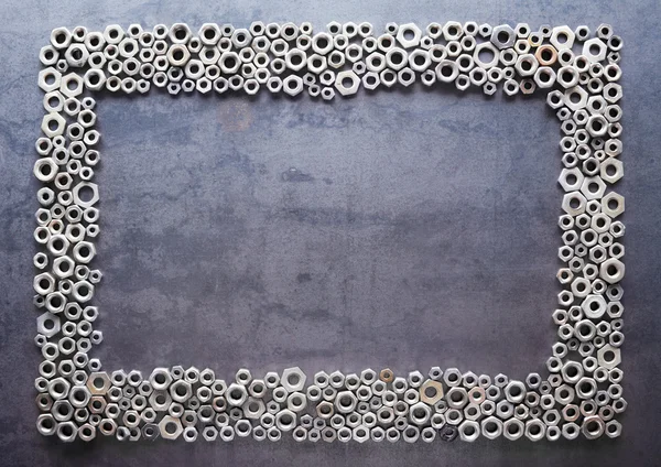 Moldura de porcas sortidas no fundo de textura metálica — Fotografia de Stock