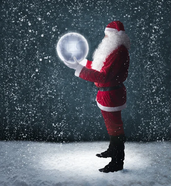 Babbo Natale tenendo incandescente pianeta terra sotto la neve che cade — Foto Stock