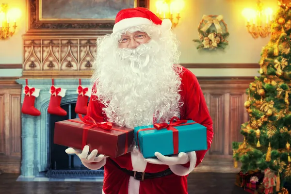 Santa Claus con regalos en la sala de estar decorada — Foto de Stock