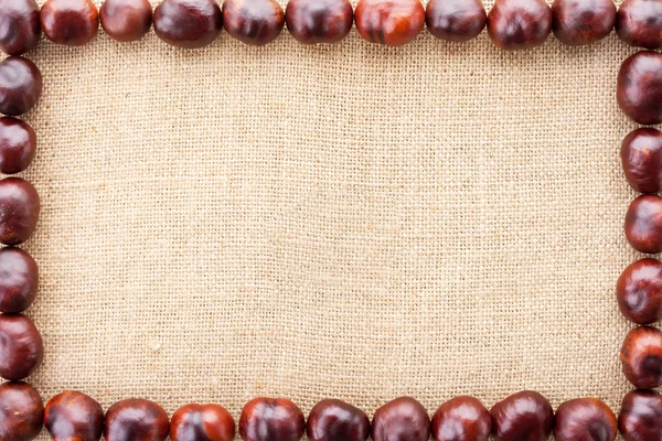 Chestnuts frame on fabric texture background — Stock Photo, Image