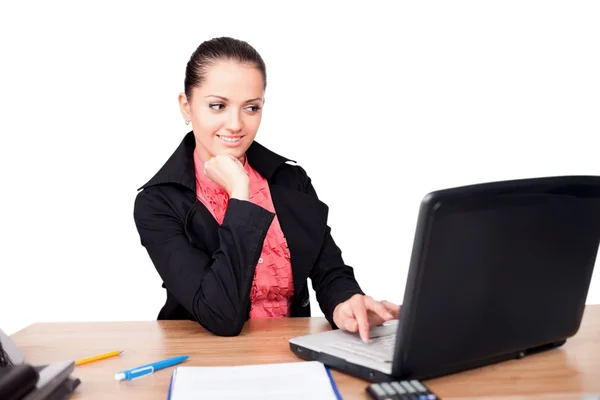 Schöne junge lächelnde Frau sitzt am Schreibtisch und arbeitet lizenzfreie Stockfotos
