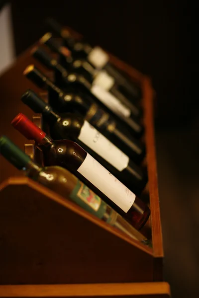 Пляшки вина, складені на дерев'яних стійках, зняті з обмеженою глибиною — стокове фото