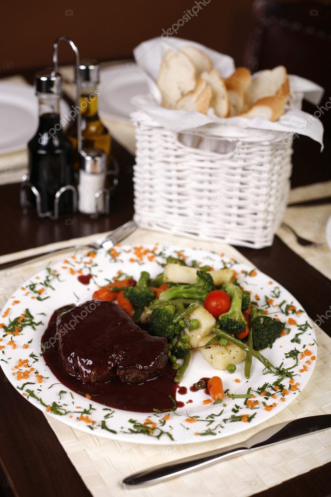 Elegant restaurant plate with a big steak and gravy garnished wi