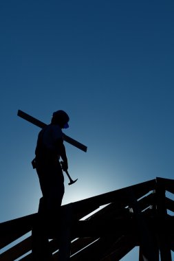 Builder working late on top of building clipart