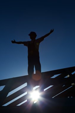 Worker on top of roof welcoming the morning clipart