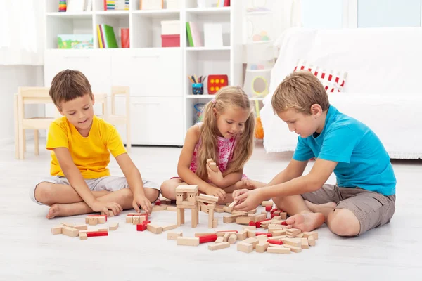 Three kids playing with wooden blocks Stock Photo