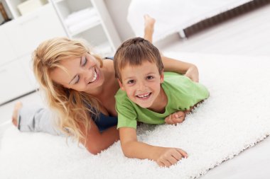 Happy mother and son playing in the living room clipart