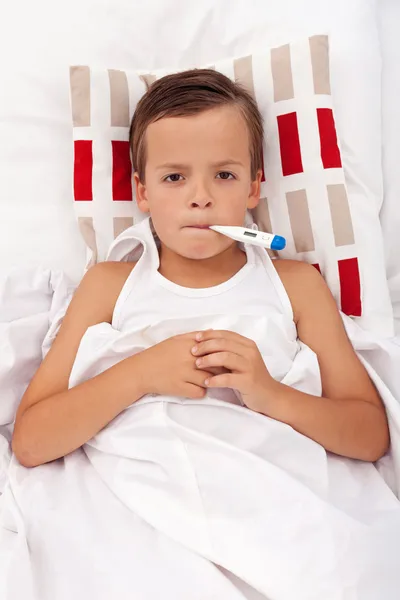 Sjukt barn i sängen med termometer — Stockfoto