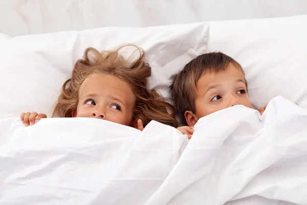 Kids afraid pulling the quilt on their heads — Stock Photo, Image