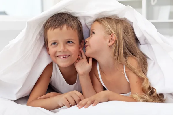 Niños compartiendo sus secretos bajo el edredón — Foto de Stock