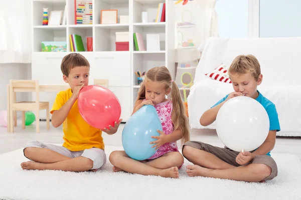 Kinder blasen große Luftballons — Stockfoto