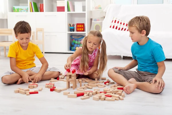 Three kids playing with wooden blocks Royalty Free Stock Images