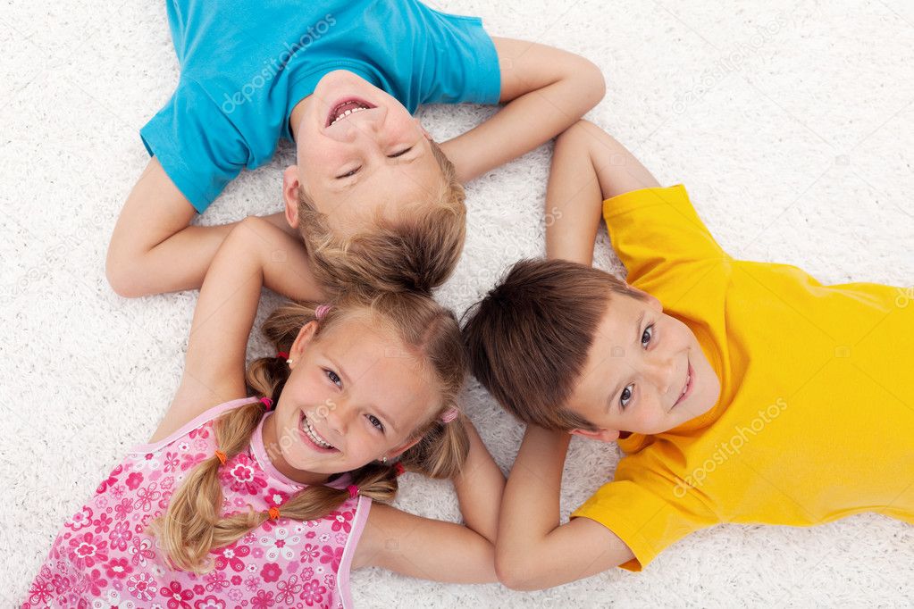 Three kids laying on the floor in circle