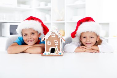 Happy kids with gingerbread house at christmas clipart