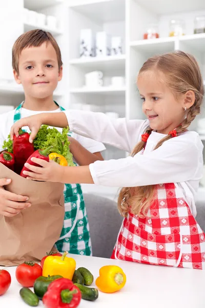 Kids unpacking vegetables in the kitchen — Stockfoto