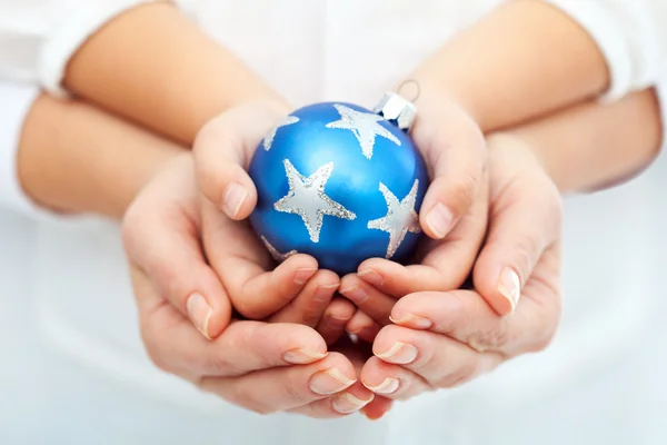 Mains d'adulte et d'enfant tenant une boule de Noël — Photo