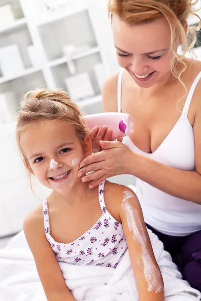 El cuidado del cuerpo - la mujer y la niña aplicando crema —  Fotos de Stock