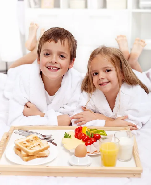 Glada barn som äter frukost i sängen — Stockfoto