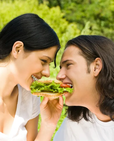 Young happy couple eating together outdoors — Stock Photo, Image