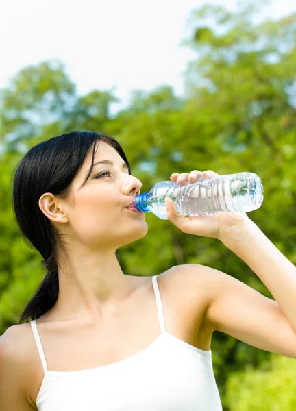 Jovem mulher bebendo água no treino, ao ar livre — Fotografia de Stock