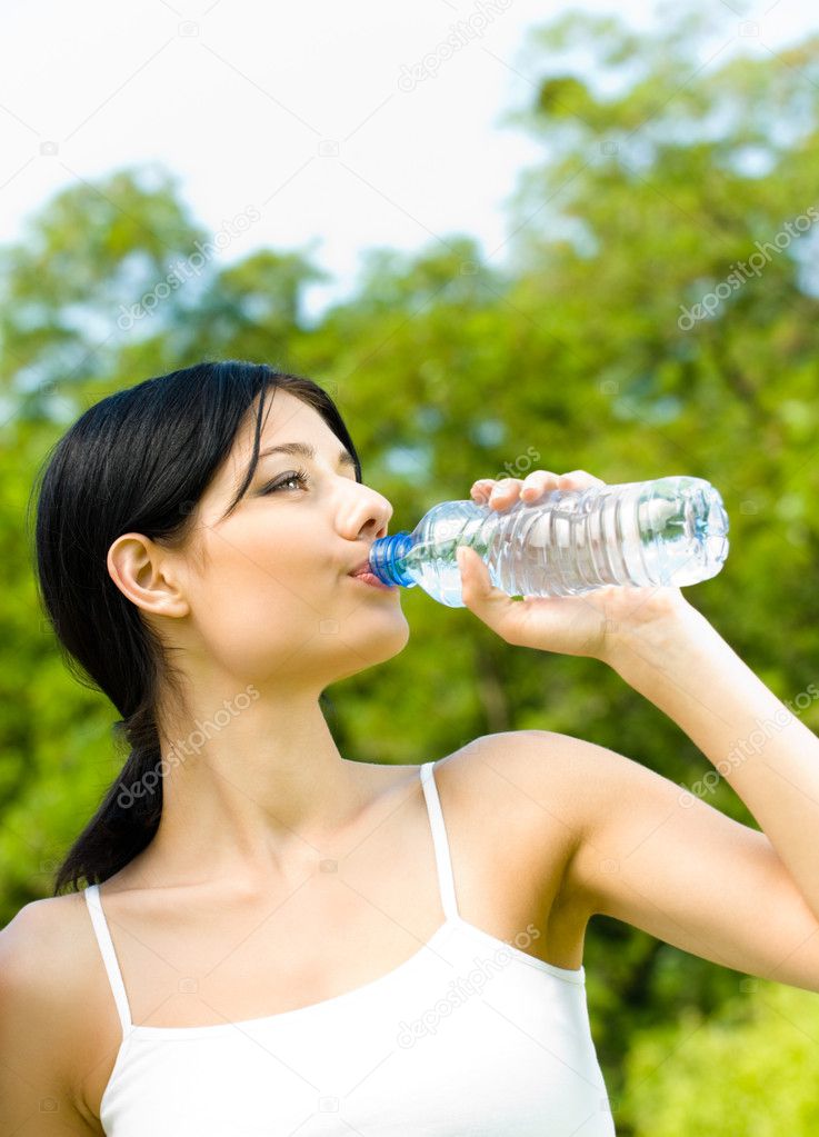 Young woman drinking water at workout, outdoors