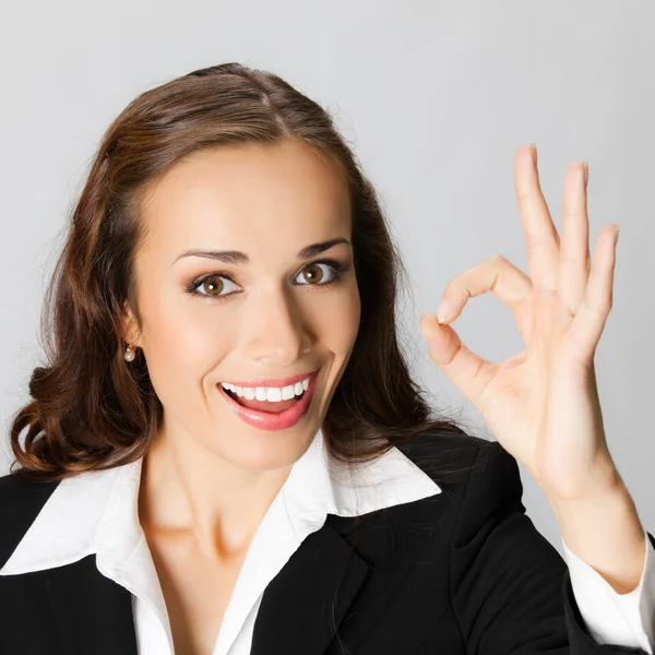 Donna d'affari felice con gesto giusto, sopra grigio — Foto Stock